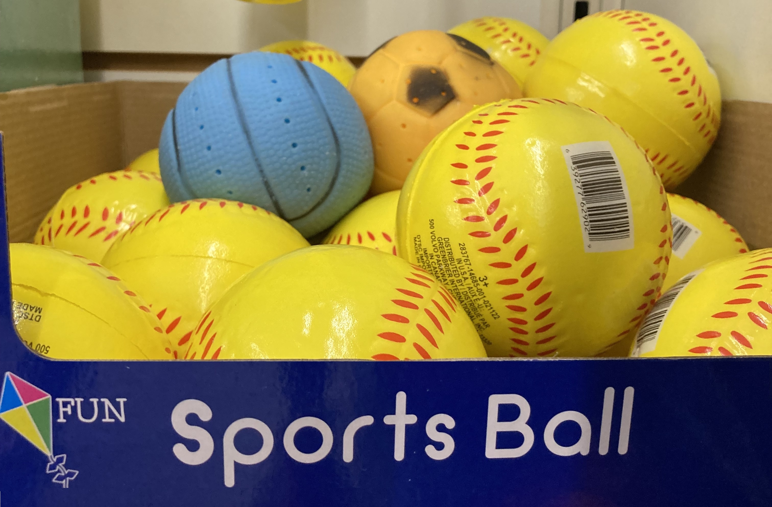 Sports bar box of yellow foam baseballs and blue basketball