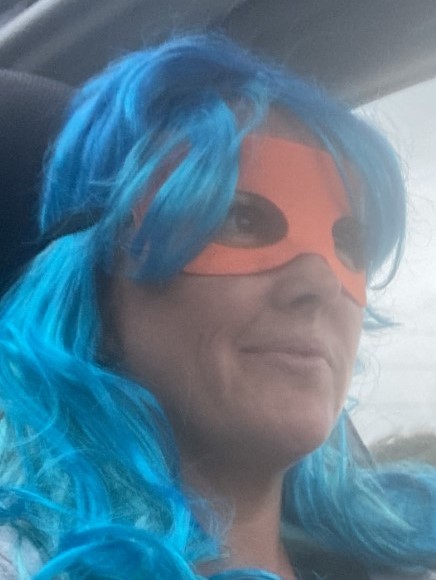 Blue hair woman in superhero mask driving car